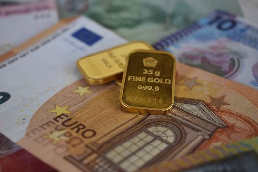 Gouden munten en een grafiek op tafel als illustratie bij nu beleggen in goud voor particuliere beleggers